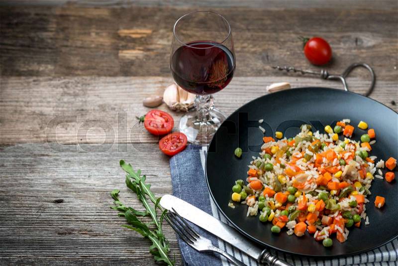 Yummy pilaf with vine and tomatoes on side, served on black plate with blue napkin, stock photo