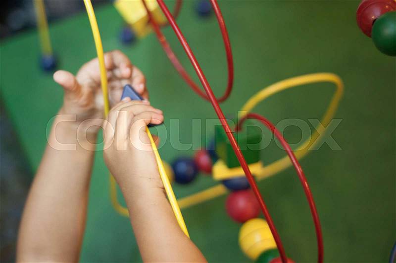 Kids hands playing Wooden Wire Maze Educational Game Toy toddler blocks, stock photo