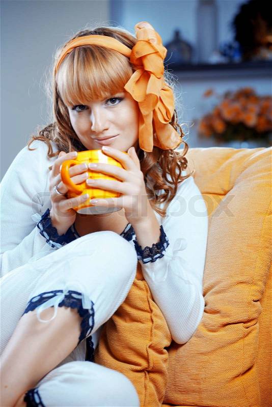 Portrait of cute pin-up housewife drinking hot tea on sofa at home, stock photo