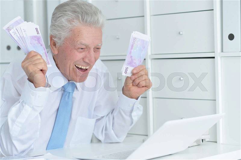 Elderly businessman working in the office with laptop, stock photo