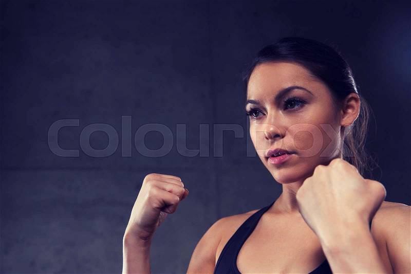 Sport, fitness, martial arts and people concept - woman holding fists and fighting in gym, stock photo
