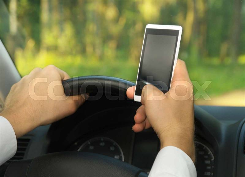 Young man uses a mobile phone, driving a car. Breaking the rules, stock photo