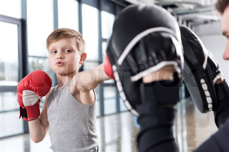 Young boy boxer practicing punches with coach , stock photo