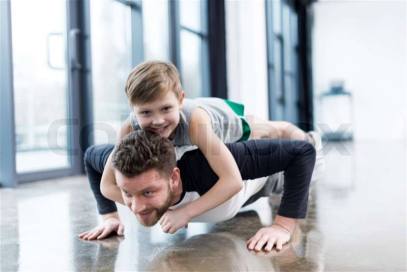Man doing push ups with boy on his back , stock photo