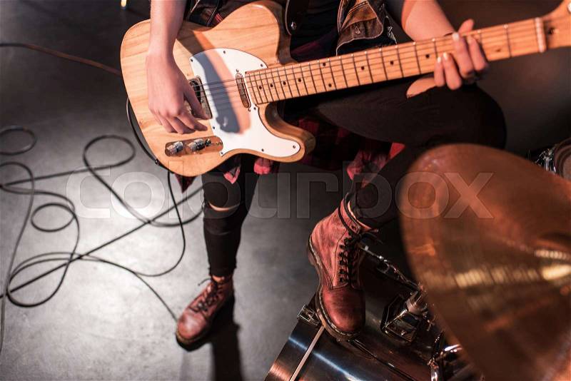 Cropped shot of rock and roll girl playing bass guitar on stage, stock photo