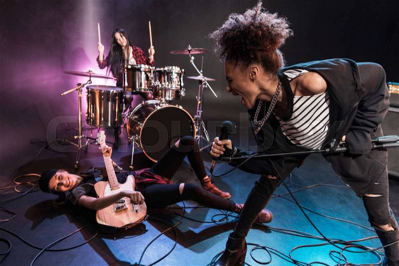 Young multiethnic rock and roll band performing concert on stage , stock photo