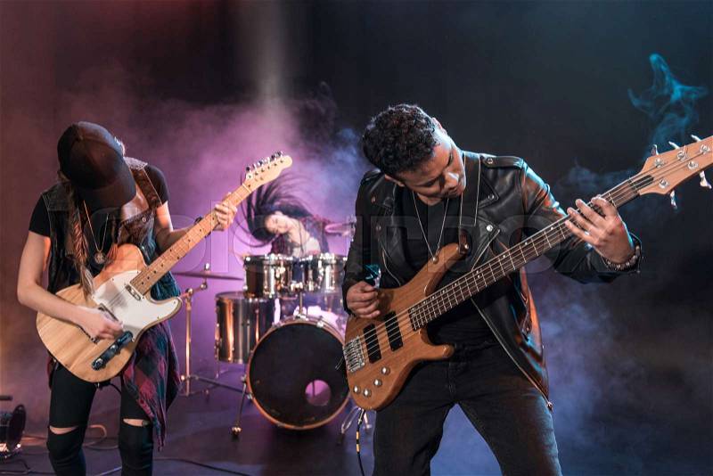 Rock and roll band with electric guitars playing hard rock music on stage, stock photo