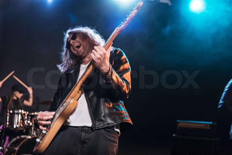 Electric guitar player with rock and roll band performing hard rock music on stage , stock photo