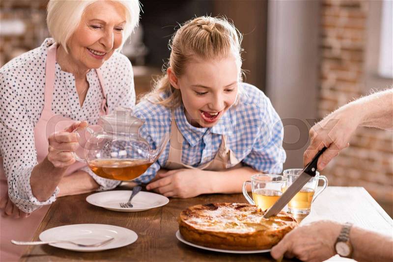 Family looking at man cutting homemade pie, stock photo