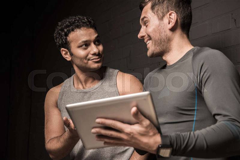 Handsome young men using tablet computer together, stock photo