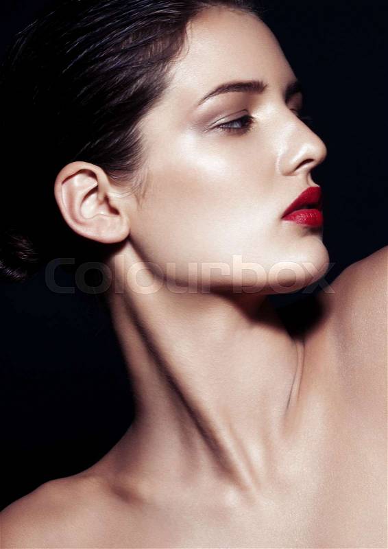 Beauty makeup fashion model with red lips profile on black background. Studio hard light with deep black shadows, stock photo