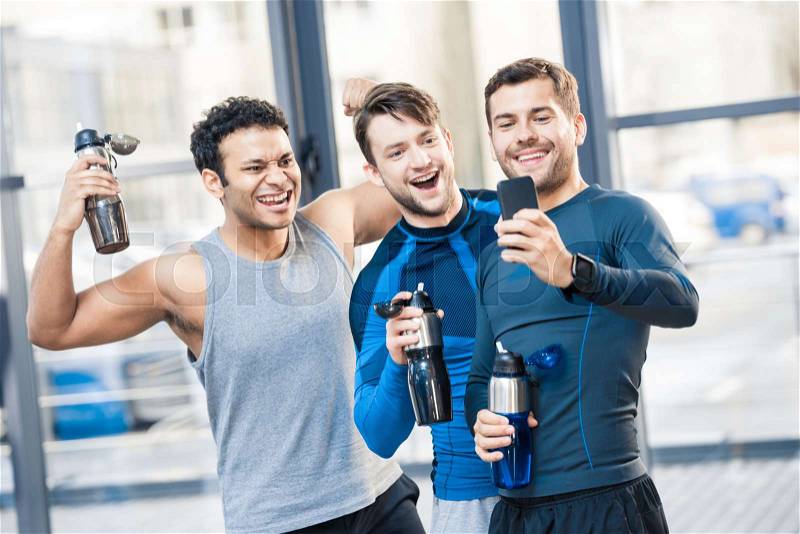 Happy three friends photographing by smartphone at sport club, stock photo