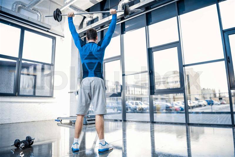 Handsome young man workout with barbell at gym, stock photo