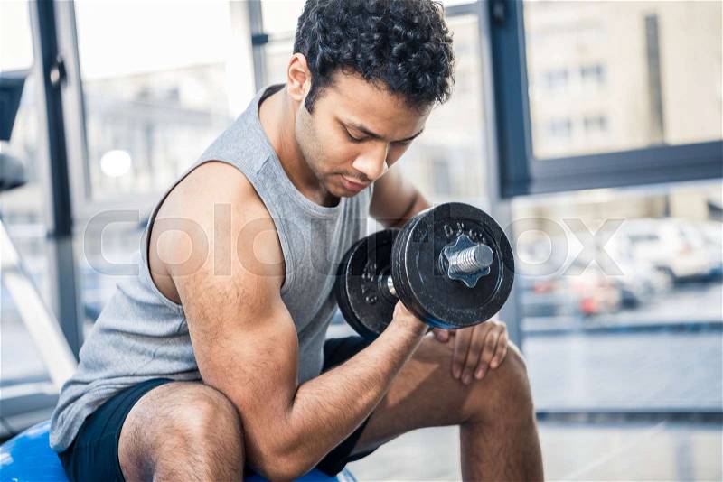 Handsome young man workout with dumbbell at gym, stock photo