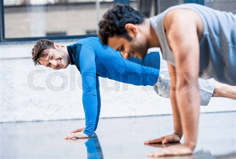 Young men doing push-up at sports center, stock photo