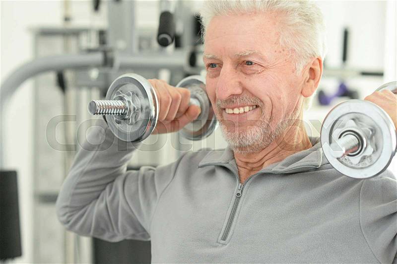 Portrait of an elderly man in a gym with dumbbells, stock photo