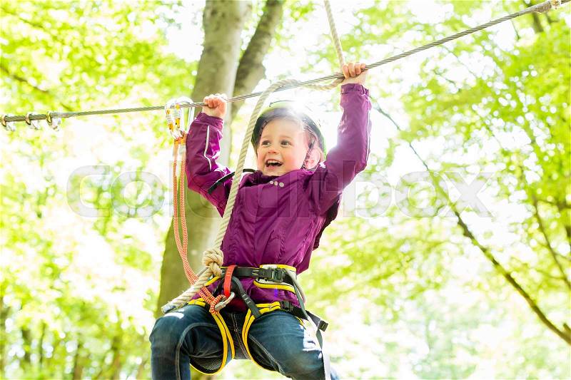 Girl climbing in high rope course enjoying the adventure, stock photo