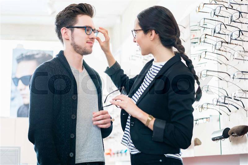 Woman and man buying glasses in optician shop, stock photo