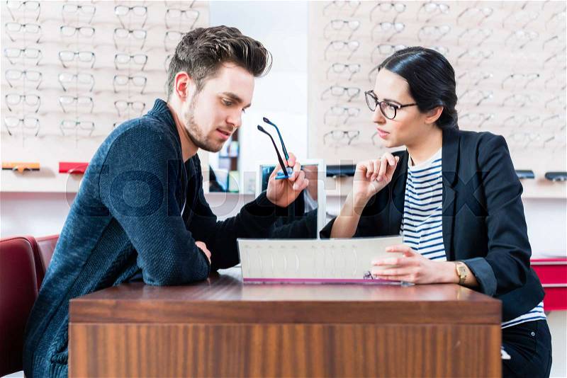 Man at optician shop getting advice from sales woman, stock photo