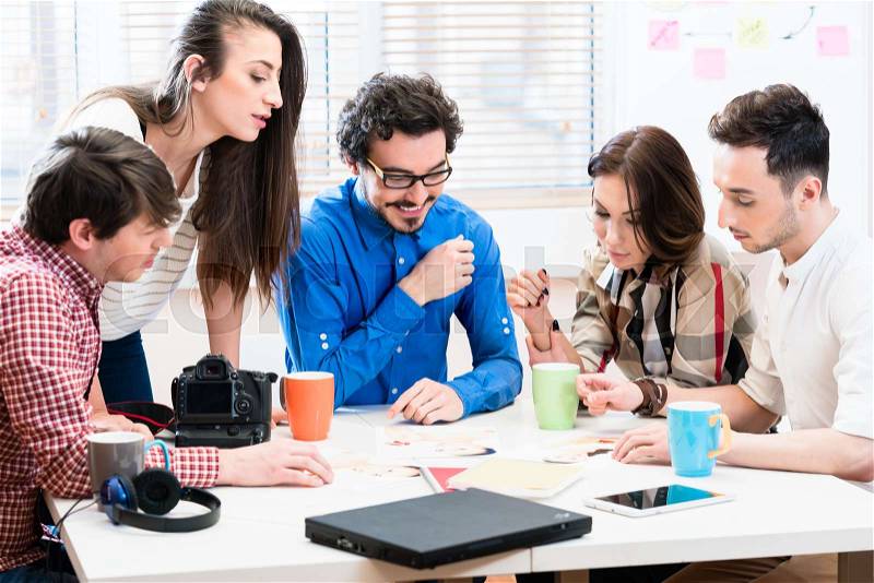 Women and men in office of creative agency developing ideas together, stock photo