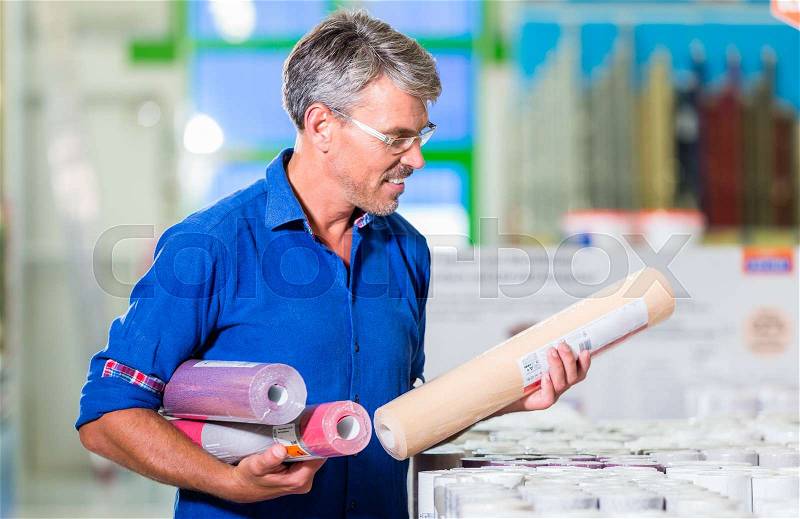Dad choosing wallpapers for girls room in home improvement store, stock photo