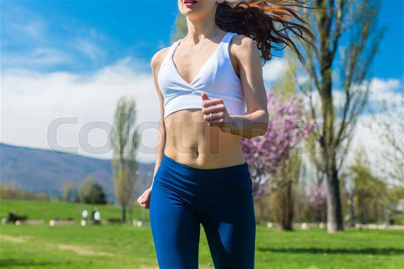 Torso of woman running or jogging on spring day, stock photo