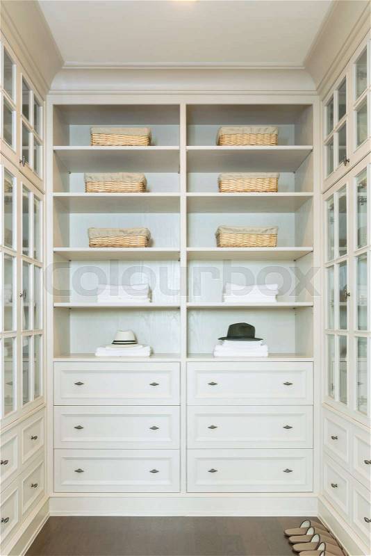 Large white walk-in closet with shelves at home, stock photo