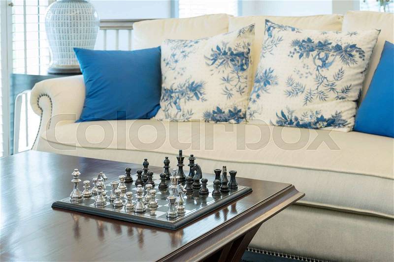 Decorative chess board with chess pieces in luxury living room interior, stock photo