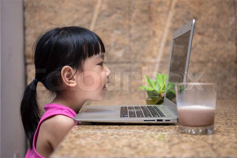 Asian little Chinese girl playing computer at home, stock photo