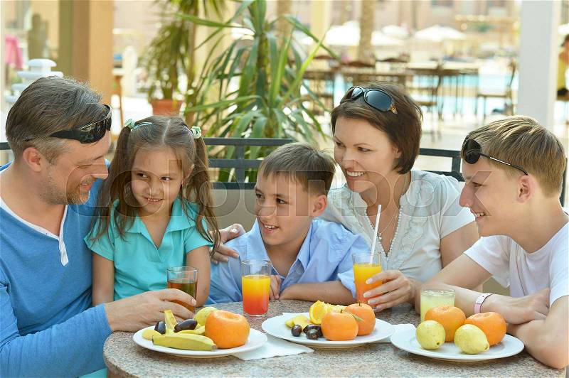 Happy parents with their children eating at the same table, stock photo