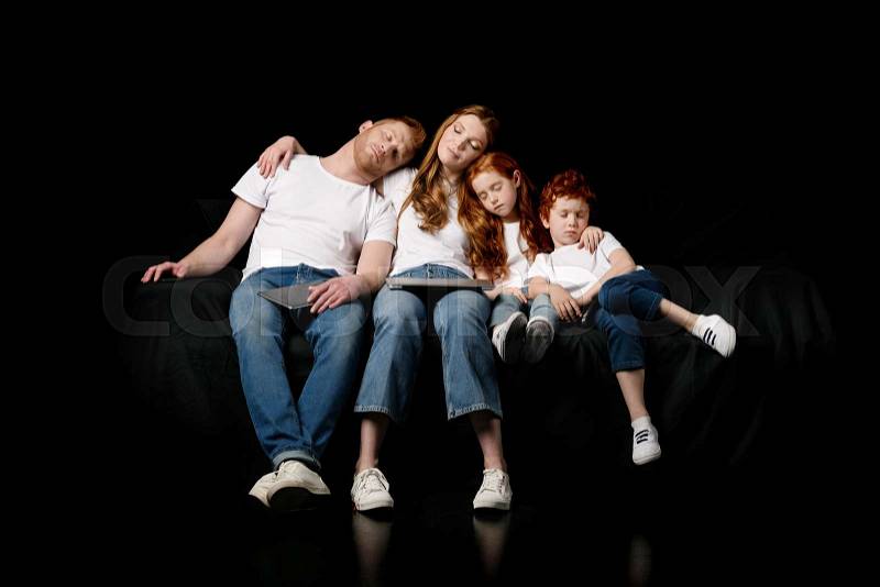Sleeping family with various digital devices isolated on black, stock photo
