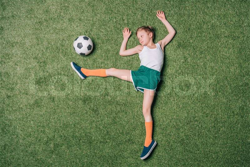 Top view of little boy pretending playing soccer on grass, athletics children concept, stock photo