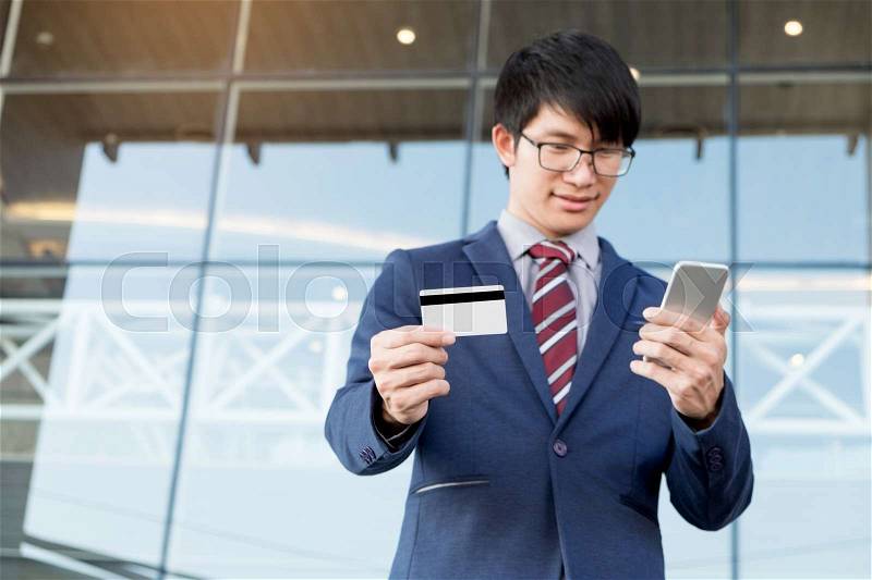 Handsome male owner of trading company dialing number from visit card on his modern smartphone searching skill specialist of financial service to make professional analysis of corporate income, stock photo