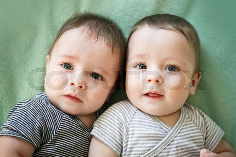 Newborn twins boys are lying on the bed, stock photo