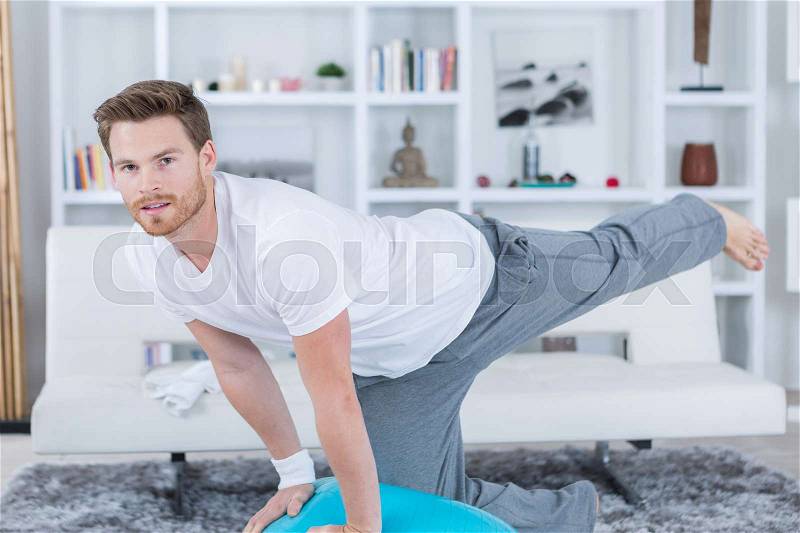 Young man in lounge room doing exercise, stock photo