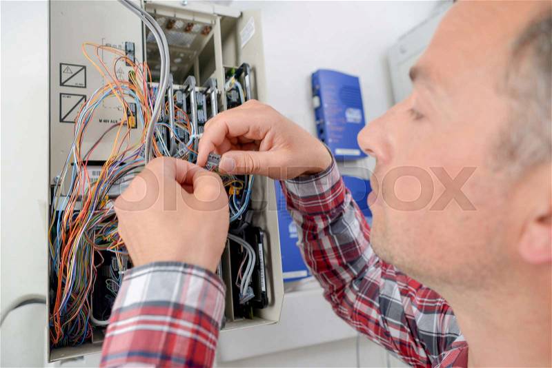 Electrician repairing a fusebox, stock photo