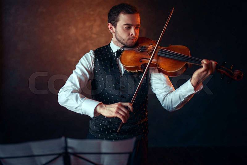 Male violinist playing classical music on violin. Fiddler man with musical instrument, stock photo