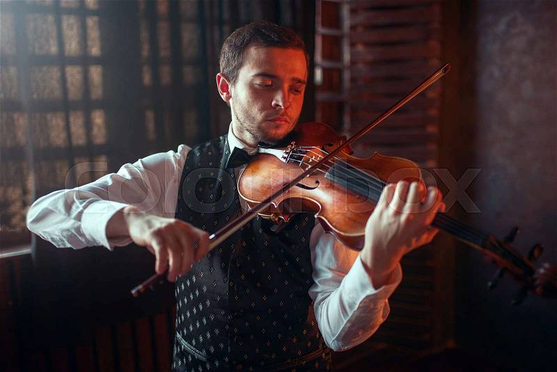 Male violinist playing classical music on violin. Fiddler man with musical instrument, stock photo