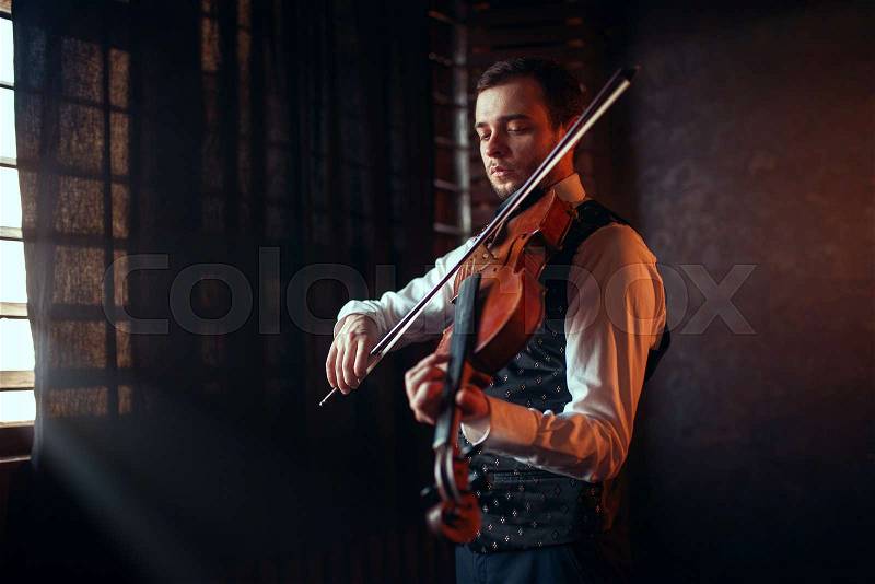 Portrait of male fiddler playing classical music on violin. Violinist man with musical instrument, stock photo