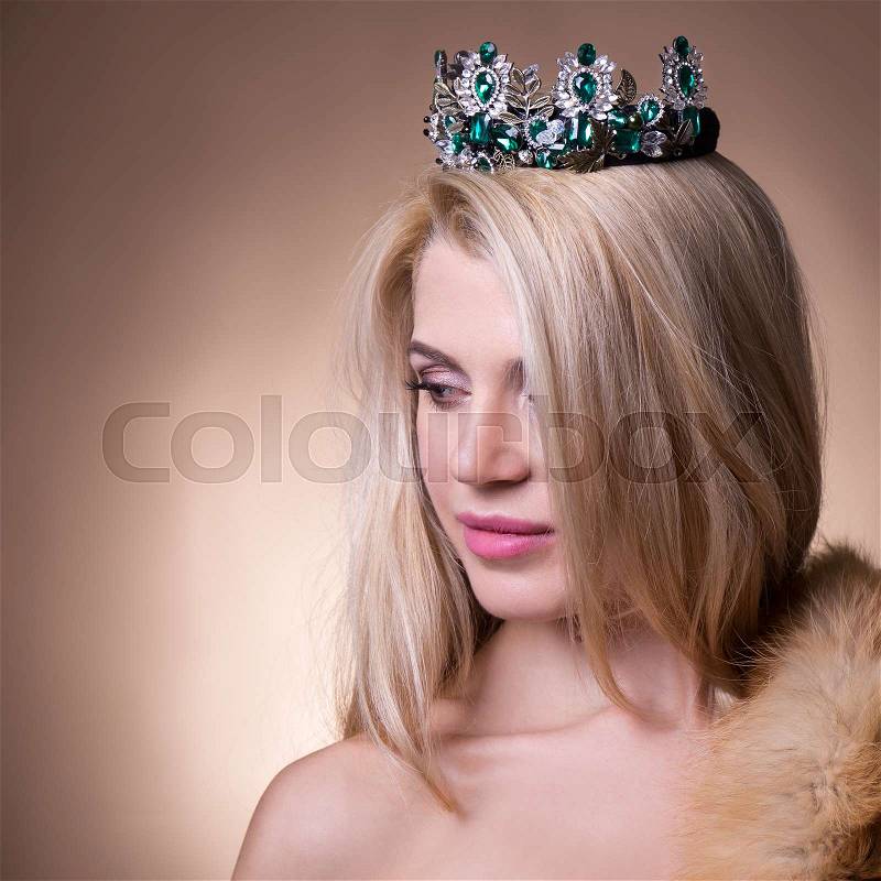 Close up portrait of young beautiful woman with crown over beige background, stock photo