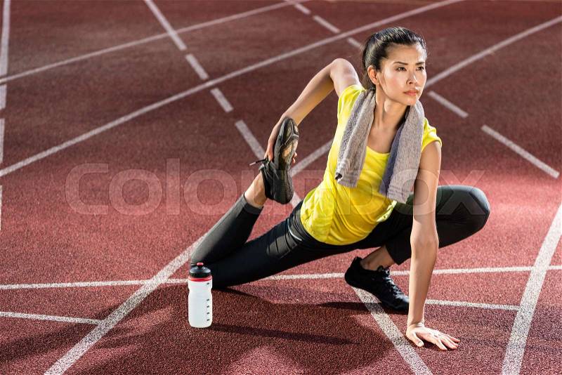 Woman sprinter doing warm up exercise before sprint, stock photo