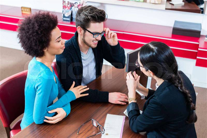Woman and man buying glasses at optician store getting advice from saleslady, stock photo