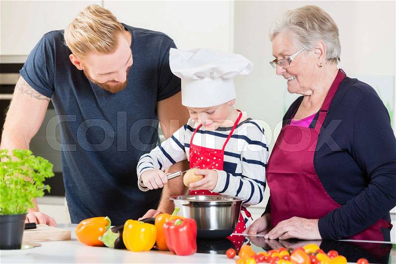 Mom, dad, granny and grandson together in kitchen preparing food, stock photo