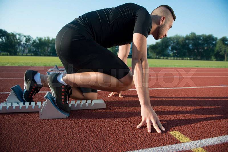 Runners preparing for race at starting blocks, stock photo