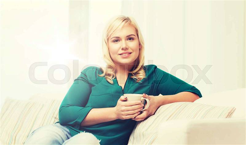People and leisure concept - happy woman with cup of tea or coffee at home, stock photo