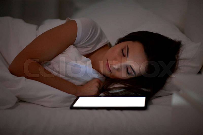 Technology and people concept - young woman with tablet pc computer sleeping in bed at home at night, stock photo
