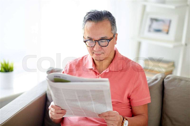 Leisure, information, people and mass media concept - happy man in glasses reading newspaper at home, stock photo