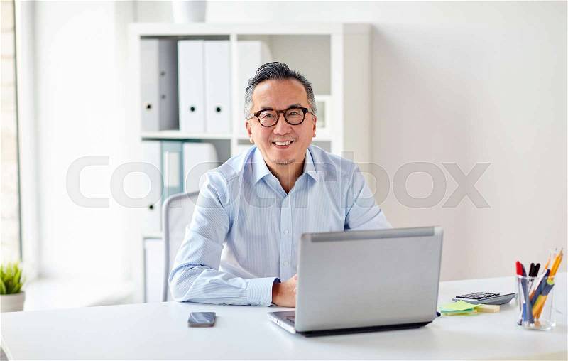 Business, people and technology concept - happy smiling businessman in eyeglasses with laptop computer office, stock photo