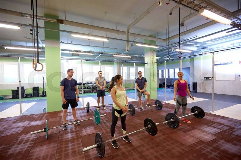 Fitness, sport, training, exercising and lifestyle concept - group of happy people with barbells in gym, stock photo