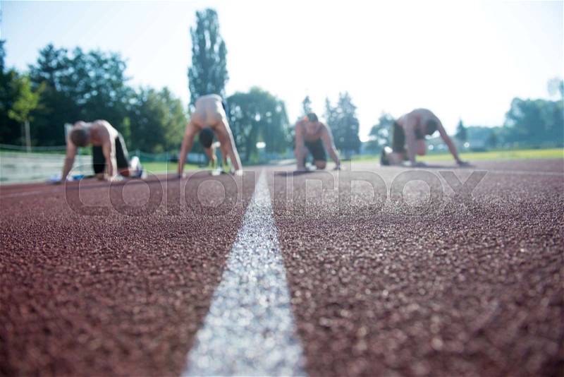 Male athletics runners on starting line without shirts, stock photo